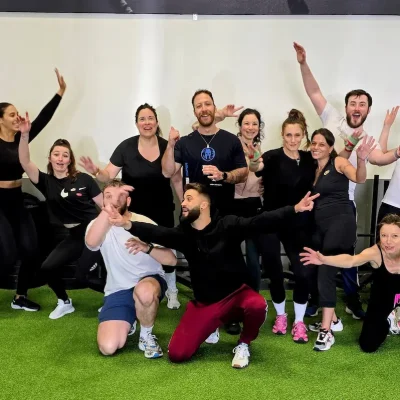 Photo de groupe en fin de séance avec un coach sportif et ses élèves dans une salle d’entraînement.